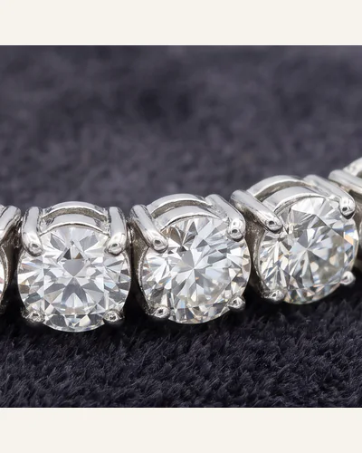 A platinum line bracelet set throughout with graduated round brilliant-cut diamonds, on charcoal velvet. — the stones.