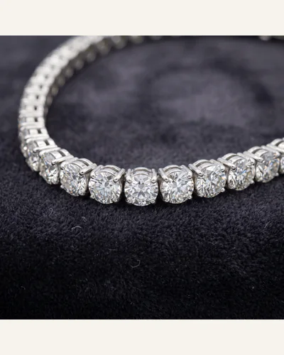 A platinum line bracelet set throughout with graduated round brilliant-cut diamonds, on charcoal velvet.