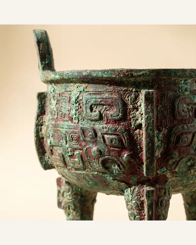 An archaic Chinese bronze ritual vessel with heavy malachite-green encrustation and taotie decoration.