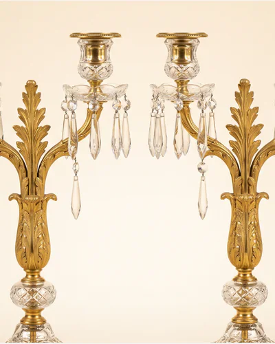 A pair of Regency ormolu and cut-glass candelabra hung with lustre drops, photographed on a warm paper plate. — the branches.