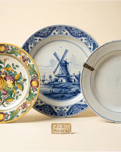 Three tin-glazed earthenware chargers propped upright, painted in cobalt and manganese.