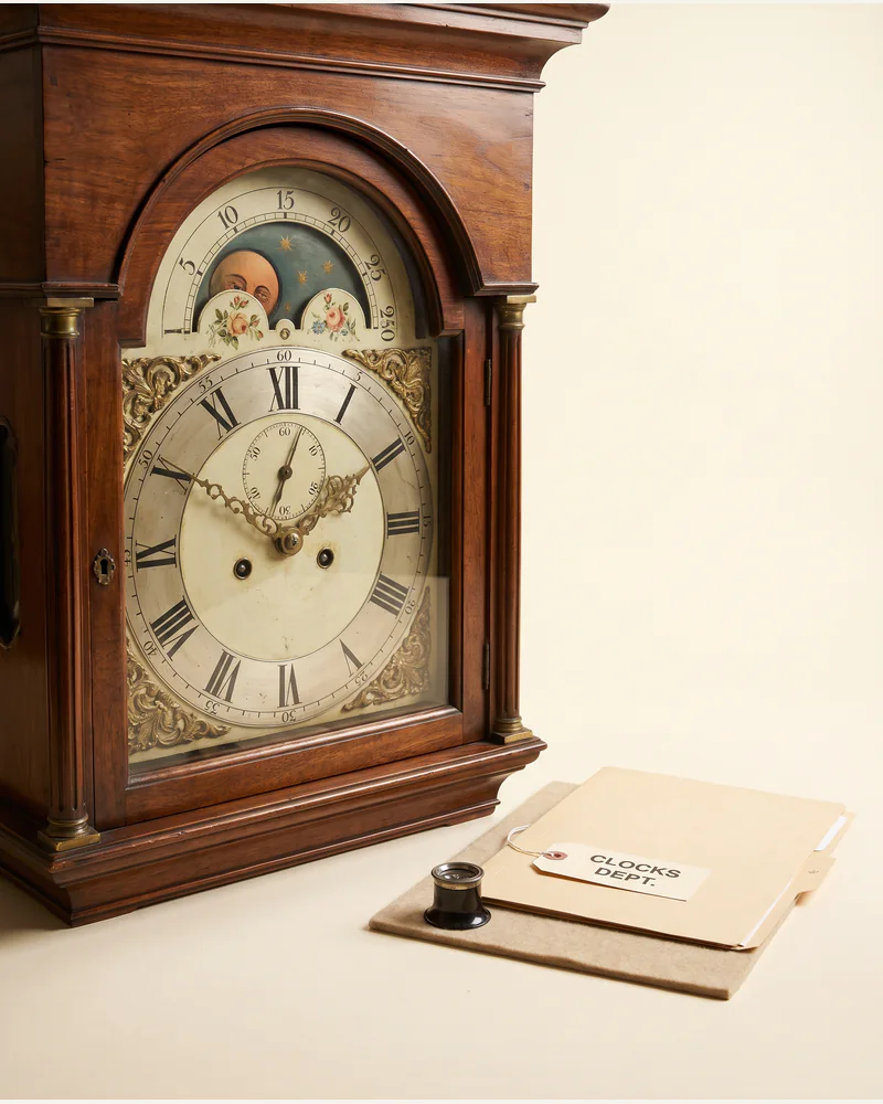 An eighteenth-century longcase clock hood with a painted arched dial and brass spandrels.