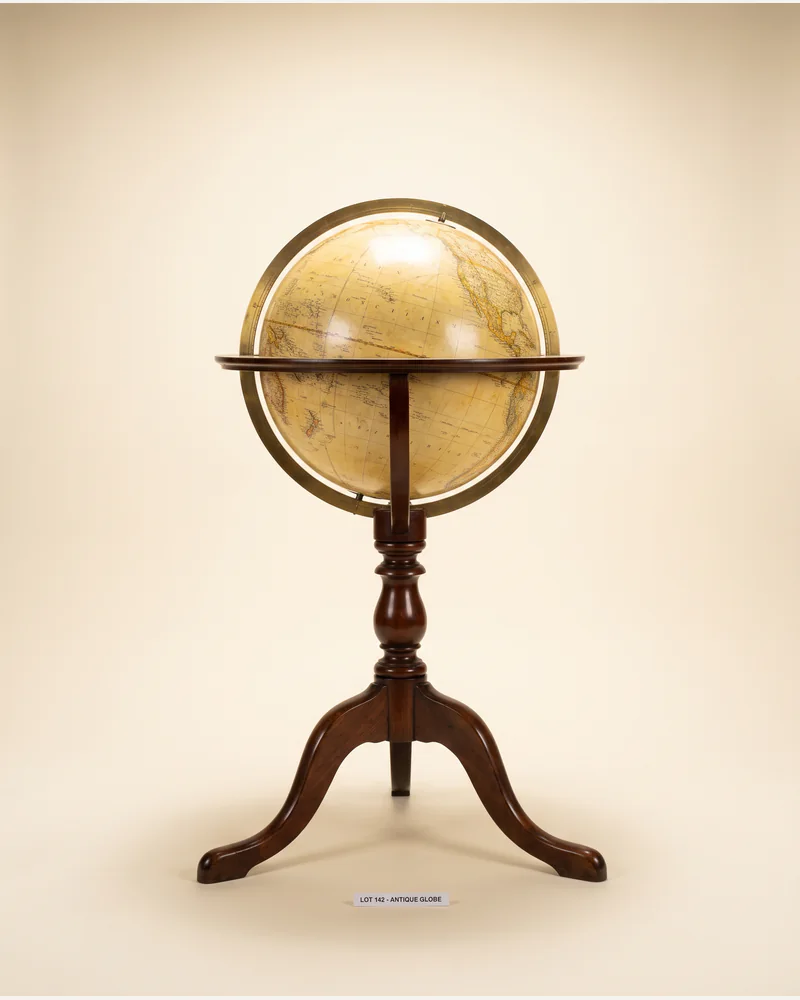 An antique terrestrial library globe on a mahogany tripod stand with a brass meridian ring.