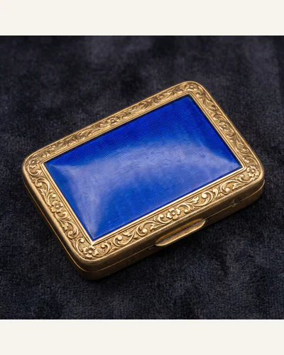 A small gold box with a translucent royal blue enamelled cover over an engine-turned ground, on charcoal velvet.