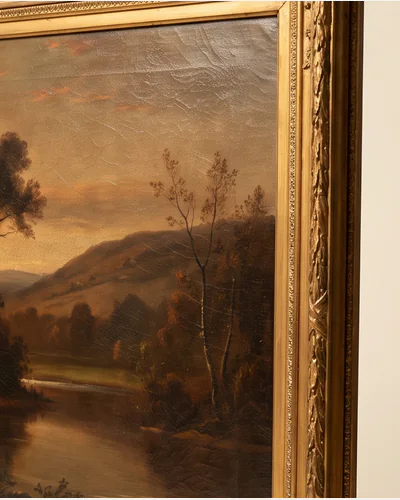 An antique oil landscape of a river valley at dusk in a carved gilt frame, photographed upright on a warm paper plate. — surface.