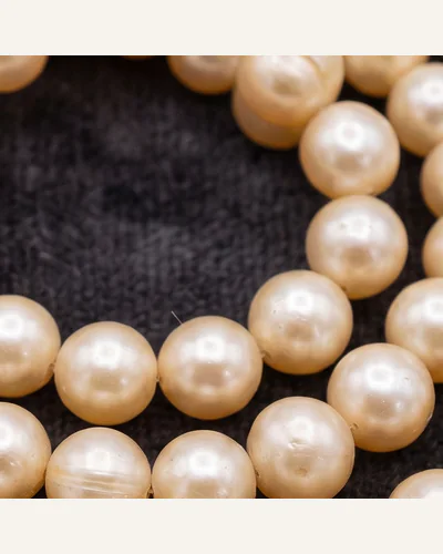 A graduated strand of natural pearls with an antique diamond-set clasp, coiled on charcoal velvet. — nacre.